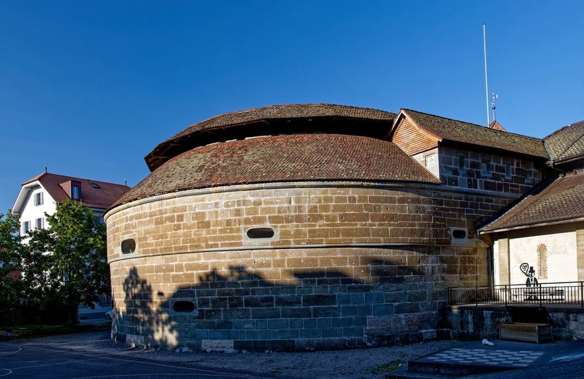 Le bastion circulaire du Belluard à Fribourg, murs de molasse et toit de tuiles sous un ciel bleu