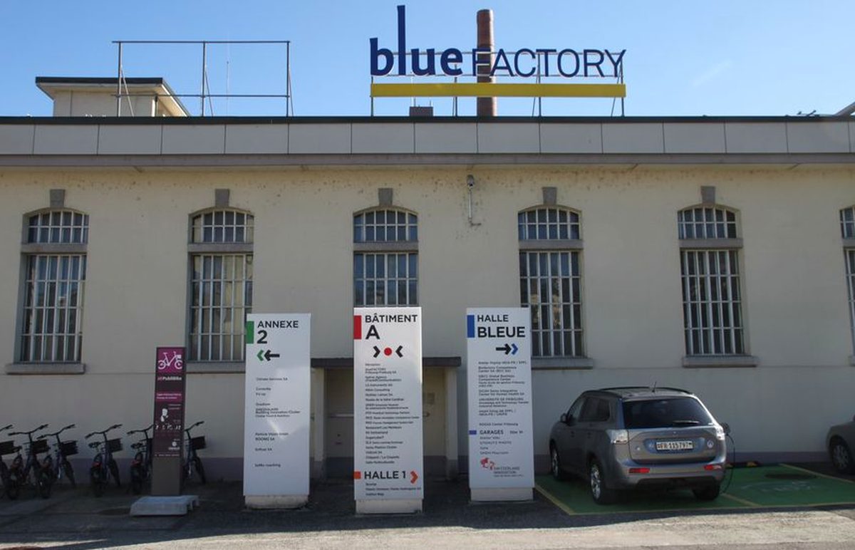 Bâtiment de bluefactory à Fribourg avec l'enseigne sur le toit et les panneaux d'orientation des halles