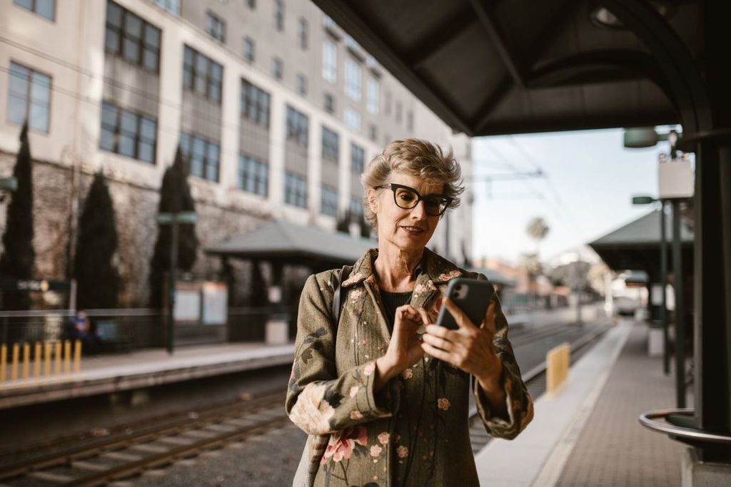 Frau schaut am Bahnhof auf ihr Smartphone