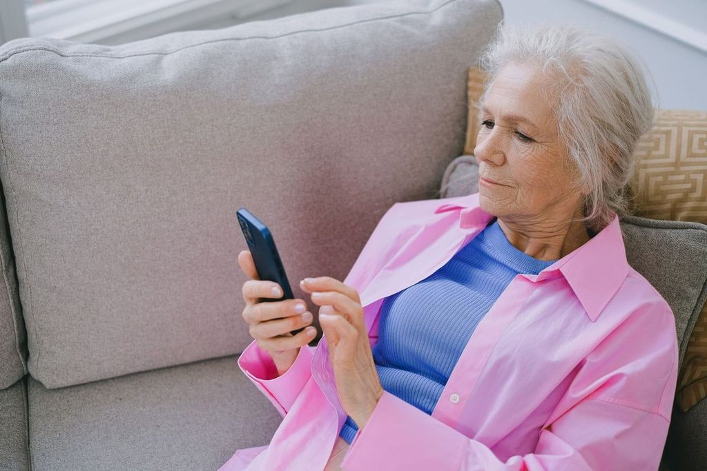 Frau prüft auf dem Sofa ein Dating-Profil auf dem Smartphone