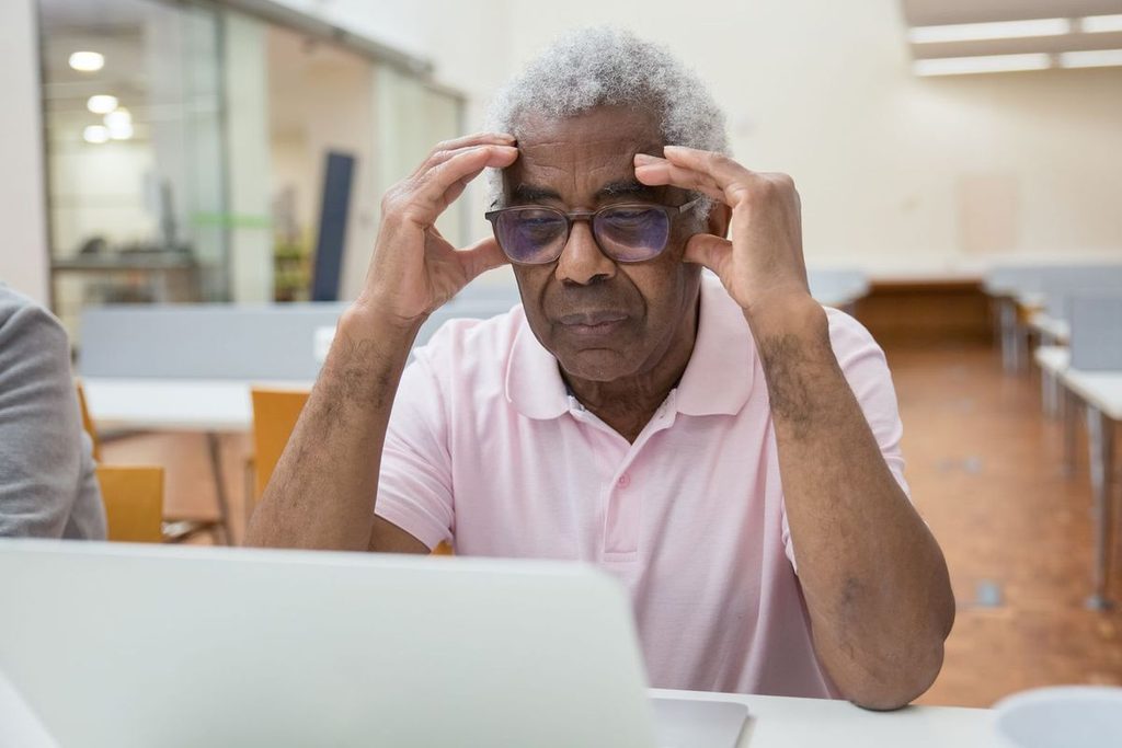 Älterer Mann sitzt besorgt vor dem Laptop