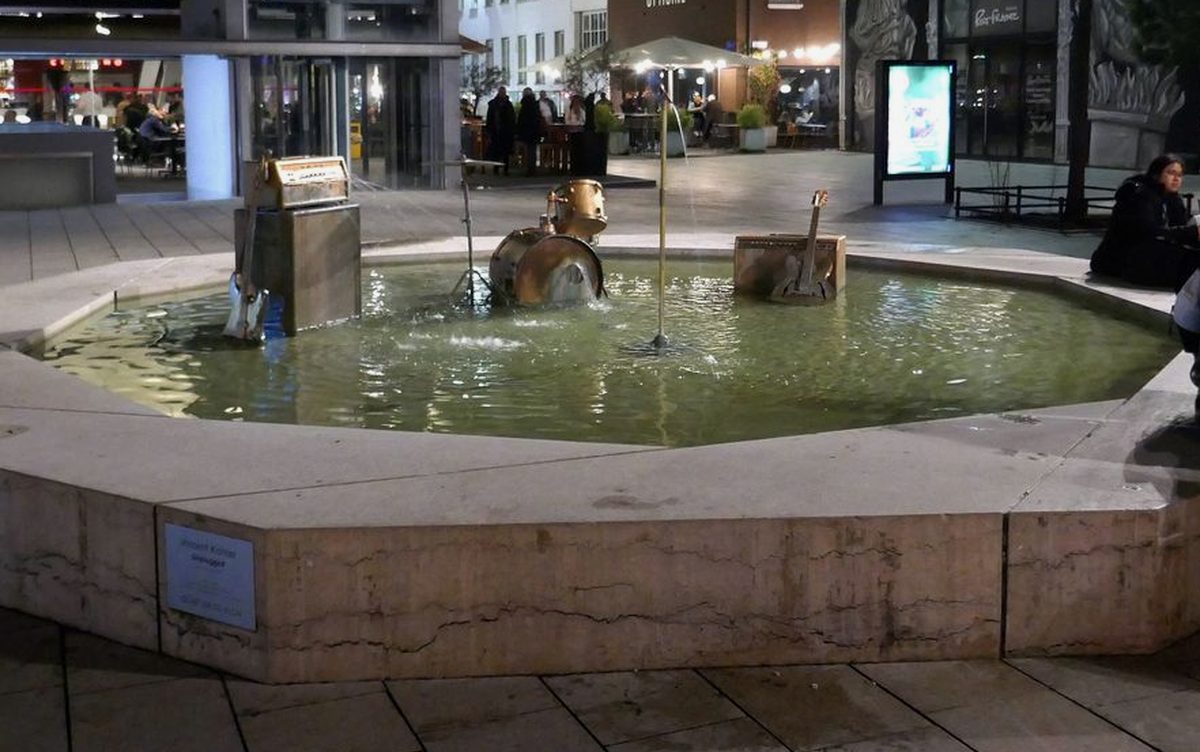 Fontaine aux instruments de musique sur l'esplanade du Flon, terrasses éclairées en soirée